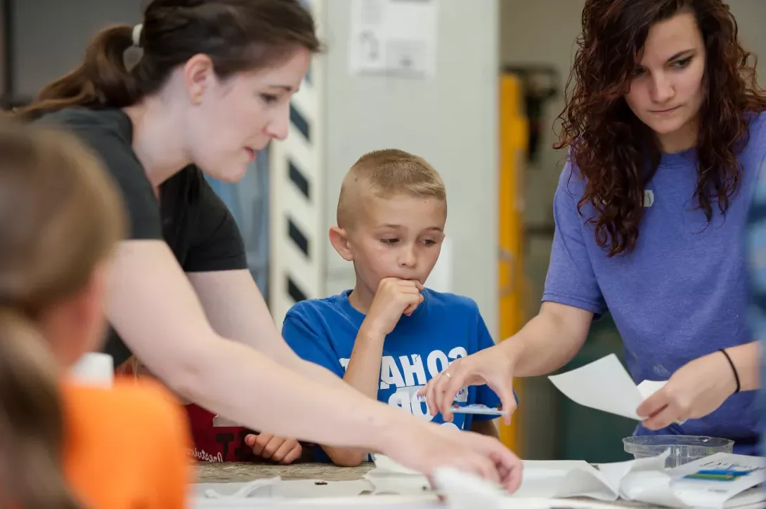 Students working with youth at art camp